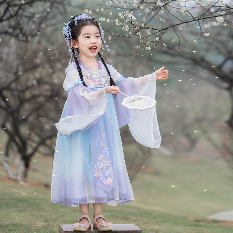 A young girl is wearing a purple silk Hanfu standing under a spring pear tree. This Hanfu skirt can be worn by girls between 1 meter and 1.5 meters tall.