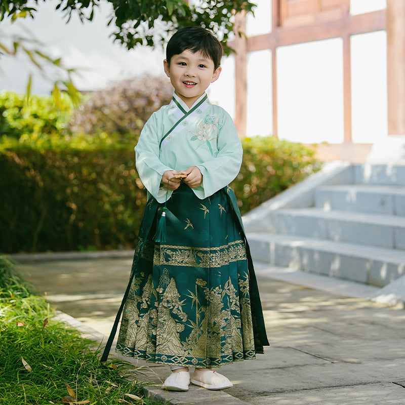 A boy model wears a light green top and a dark green mamian skirt with golden embroidery patterns, feeling the atmosphere of traditional Chinese culture