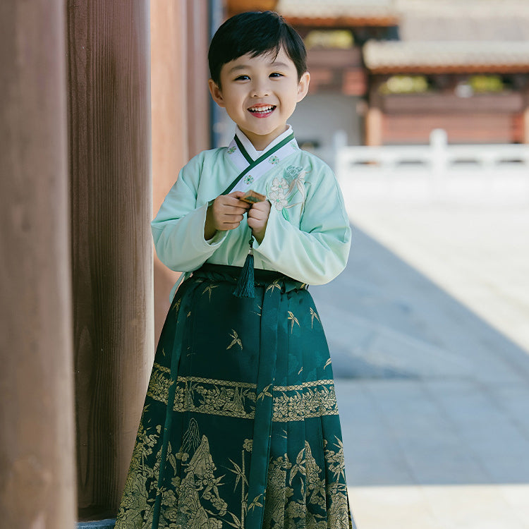 A boy wears a green Chinese Hanfu. This Hanfu depicts Chinese bamboo and mountains on the Hanfu. It is made with heavy craftsmanship and has high quality