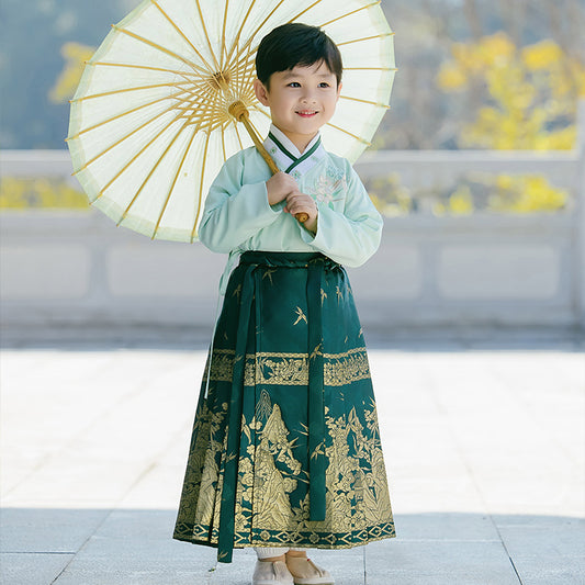 A green boy's mamainqun skirt is paired with a top with bamboo embroidery. There are exquisite golden embroidery patterns on the mamian skirt: mountains, wild geese