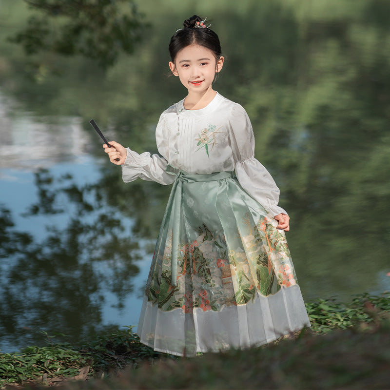 A little girl dressed in a green mamianqun and white french top, suit for spring outside