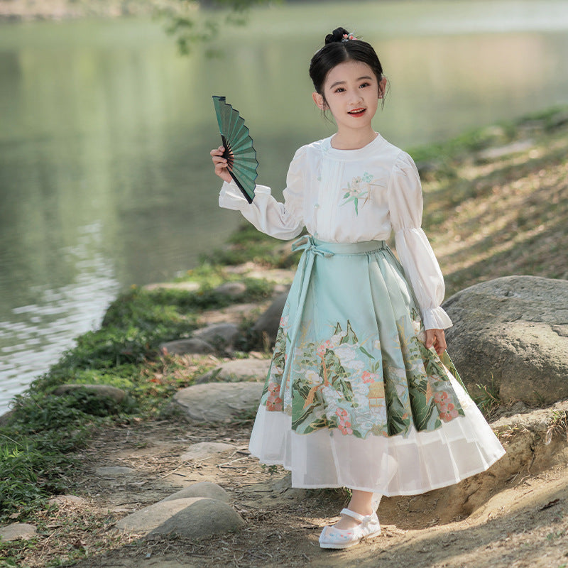 A young girl wearing a china traditional green dress with hand gold embroidery